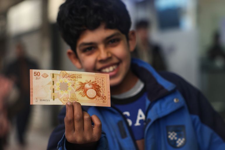 new Syria pound A boy shows a newly issued 50-Syrian-pound banknote in Damascus, Syria, Saturday, Jan. 3, 2026. (AP Photo/Ghaith Alsayed)